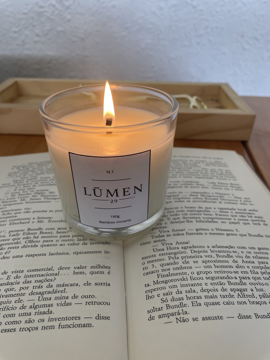 Vela LŪMEN 29 de 180 g acesa sobre um livro aberto